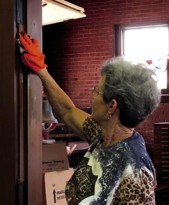 Linda Trigalet uses the original stain formula of the restored train depot.