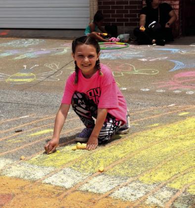 A young girl chalks up Main Street (Route 66) during the Tabouleh Fest .