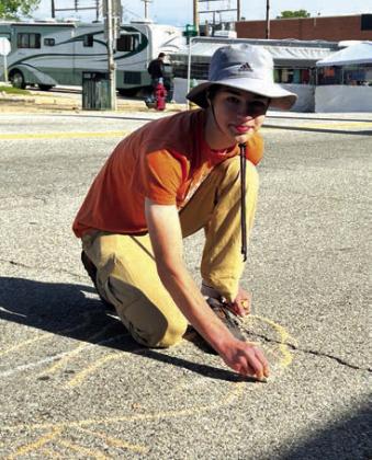 Micah Greco, 15, draws a Dimetrodon, ancient dinosaur-type creature, in chalk.