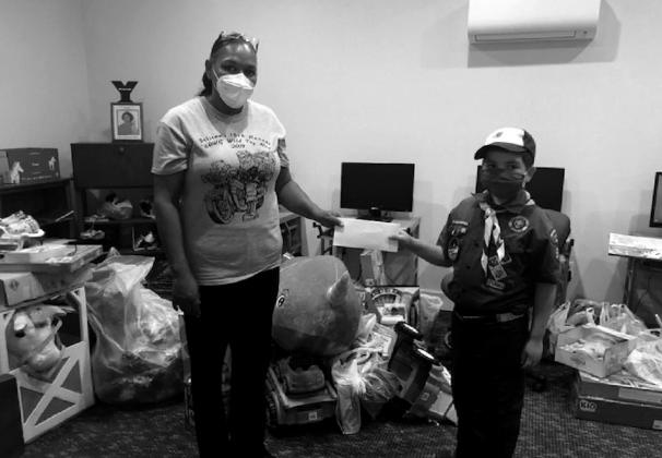 Jackson Wicker, a Bear Scout with Pack 571, presents Wal-Mart gift cards to Bristow Social Services Director Toni Godwin while posing in front of the collected toy donations. courtesy photo