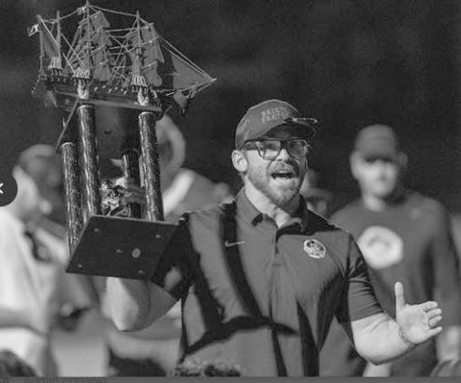 Coach Chris Jones proudly displays the Battle of the Boat’s trophy.