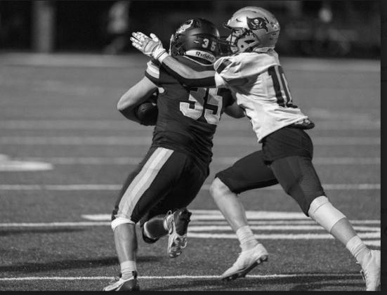 Shane Bethel hangs onto the ball while getting tackled from behind.