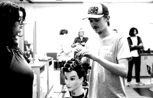 Students take turns putting rollers in a mannequin’s hair.