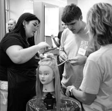 A camper tries his hand at giving a mannequin a trim.