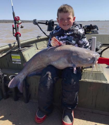 Theyoungfishermanproudlydisplayshisbluecatfishcatch.